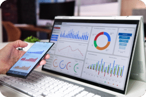 Dashboard de análise de dados e KPIs em tela de notebook e smartphone, mostrando gráficos de vendas, funil de conversão (Awareness, Purchase, Loyalty) e métricas de desempenho.